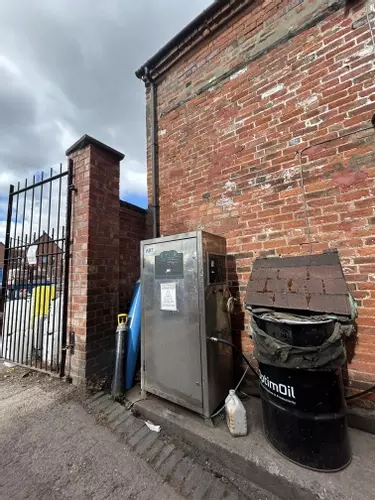 Nilfisk DTE static pressure washer in a brewery courtyard in Burton prior to flue extension installation, where boiler exhaust fumes were building up in the confined wash area during high-temperature keg cleaning.
